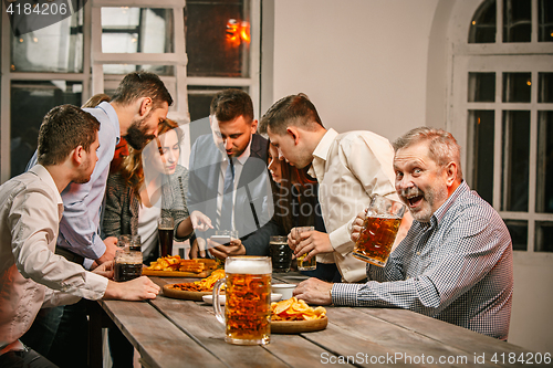 Image of Group of friends enjoying evening drinks with beer