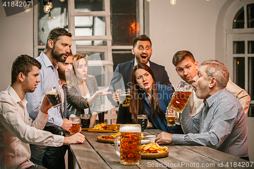 Image of Group of friends enjoying evening drinks with beer