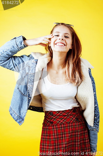 Image of young pretty teenage hipster girl posing emotional happy smiling on yellow background, lifestyle people concept