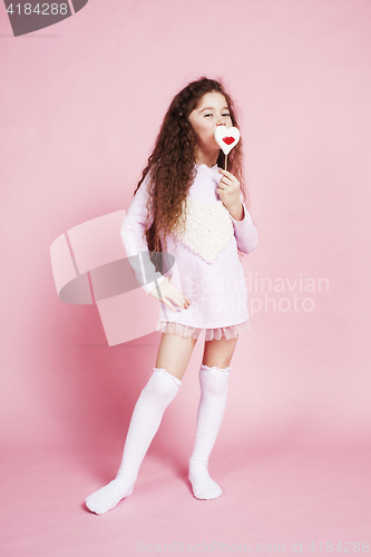 Image of little cute girl with candy on pink background posing emotional,
