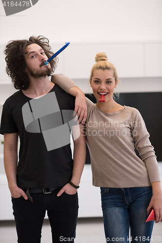 Image of couple in party hats blowing in whistle