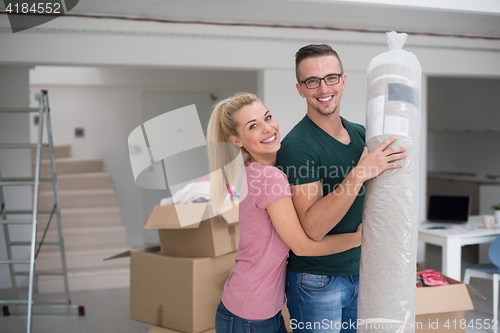 Image of couple carrying a carpet moving in to new home