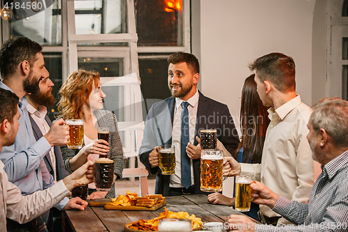 Image of Group of friends enjoying evening drinks with beer