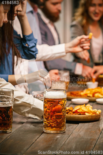 Image of Group of friends enjoying evening drinks with beer