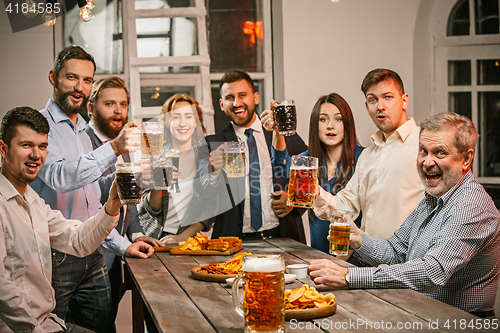 Image of Group of friends enjoying evening drinks with beer