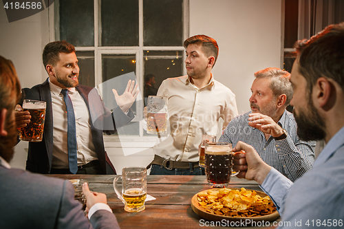 Image of Group of friends enjoying evening drinks with beer