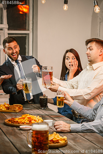 Image of Group of friends enjoying evening drinks with beer