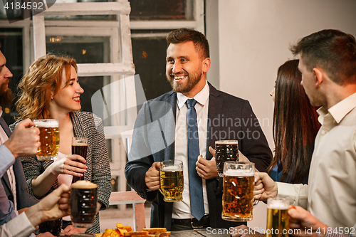 Image of Group of friends enjoying evening drinks with beer