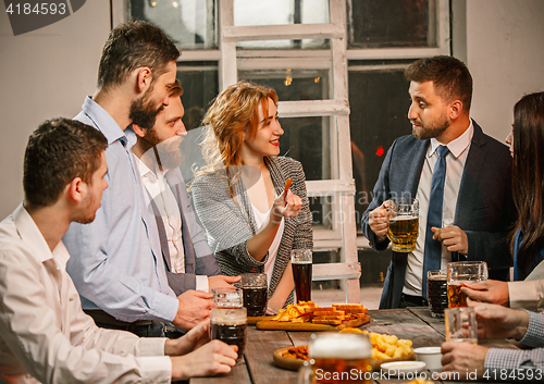 Image of Group of friends enjoying evening drinks with beer