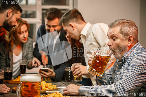 Image of Group of friends enjoying evening drinks with beer