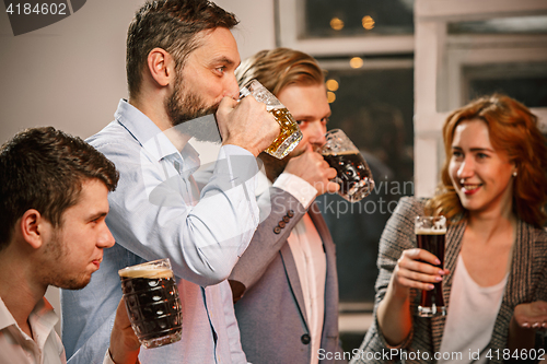 Image of Group of friends enjoying evening drinks with beer