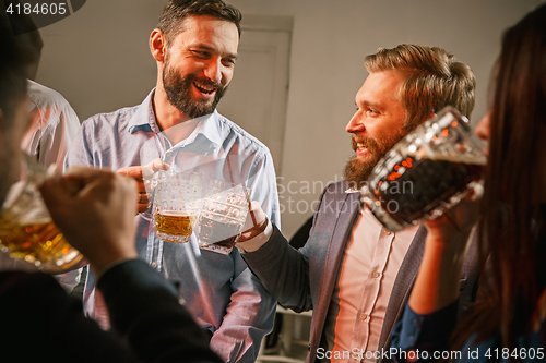 Image of Group of friends enjoying evening drinks with beer