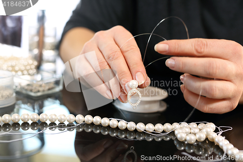 Image of Jeweler, a pearl necklace Pearl earrings, a jeweler creates jewelry