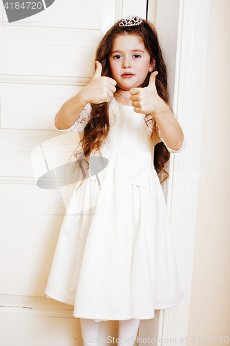 Image of little cute girl at home, opening door well-dressed in white dre