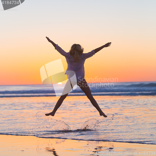 Image of Young beautiful woman jumping in the beach.