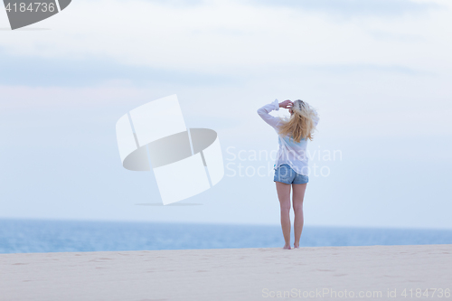 Image of Woman on sandy beach in white shirt at dusk. 