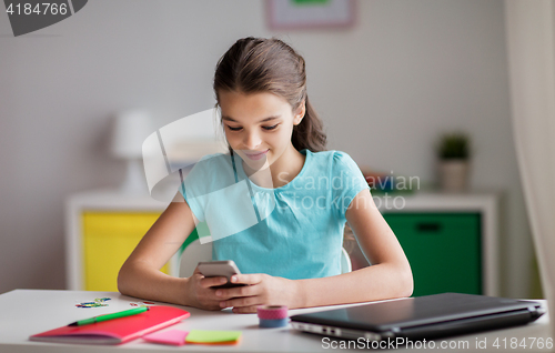 Image of girl with smartphone distracting from homework