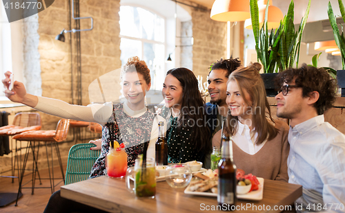 Image of friends taking selfie by smartphone at bar or cafe