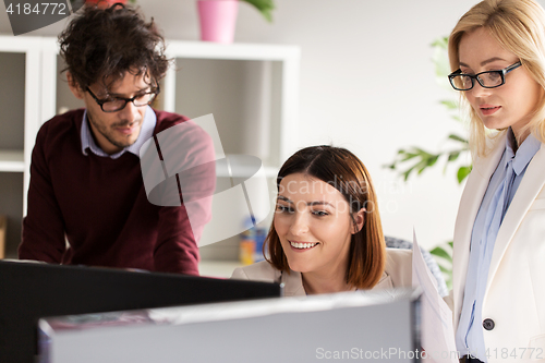 Image of happy creative team with computer in office