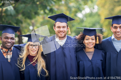 Image of happy students or bachelors in mortar boards