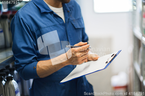 Image of auto mechanic with clipboard at car workshop