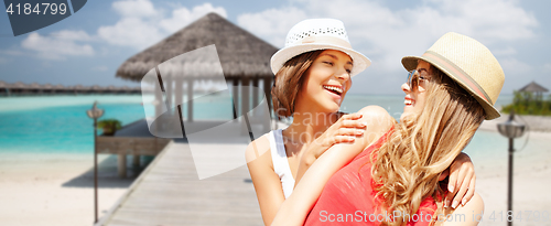 Image of smiling young women in hats on beach