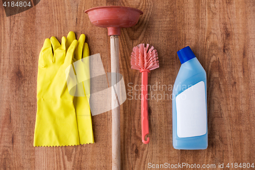 Image of plunger with cleaning stuff on wooden background