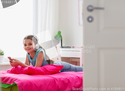 Image of girl in headphones and smartphone at home