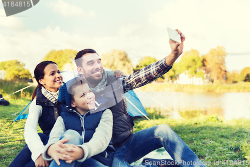 Image of family with smartphone taking selfie at campsite