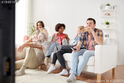 Image of friends with popcorn and beer watching tv at home