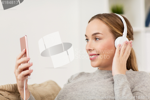 Image of woman with smartphone and headphones at home