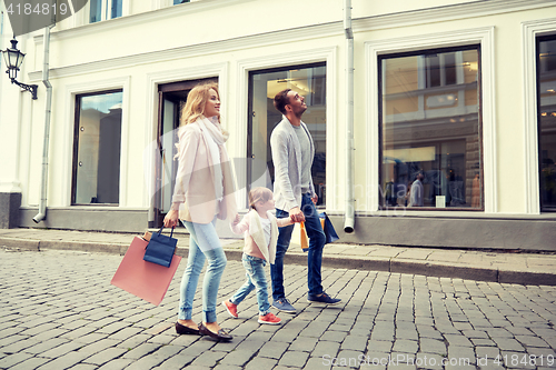 Image of happy family with child and shopping bags in city