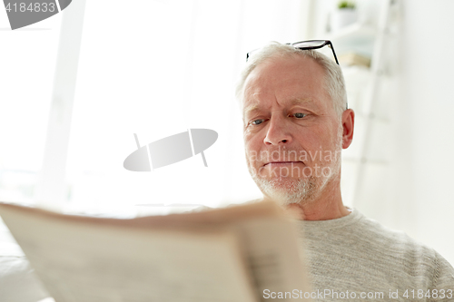 Image of close up of senior man reading newspaper at home