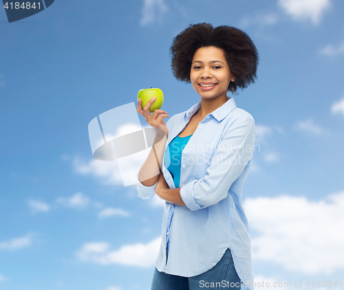 Image of happy african american woman with green apple