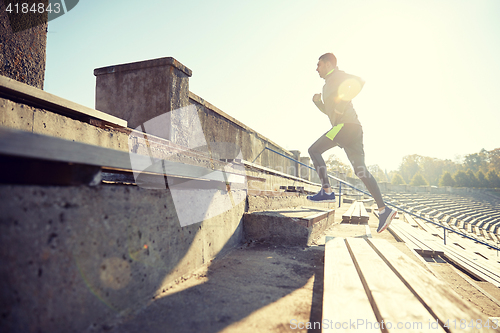 Image of happy young man running upstairs on stadium