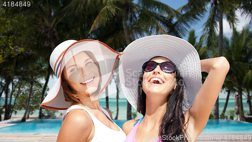 Image of happy young women in hats on summer beach