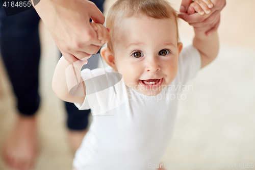 Image of happy baby learning to walk with mother help