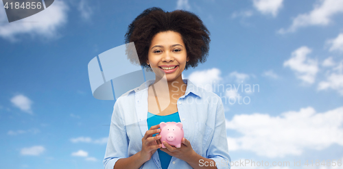 Image of happy afro american young woman with piggy bank