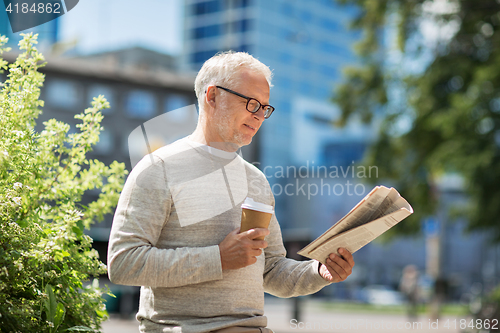 Image of senior man reading newspaper and drinking coffee