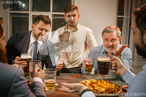 Image of Group of friends enjoying evening drinks with beer