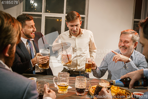 Image of Group of friends enjoying evening drinks with beer