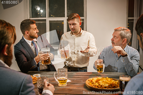 Image of Group of friends enjoying evening drinks with beer