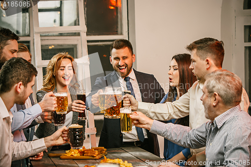 Image of Group of friends enjoying evening drinks with beer