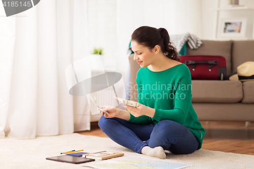 Image of happy woman with money and travel map at home