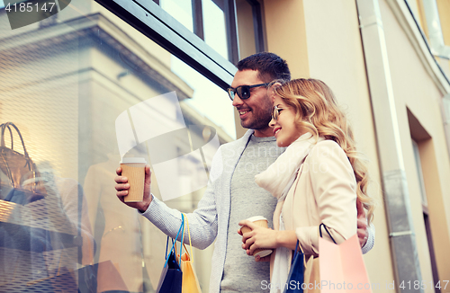 Image of happy couple with shopping bags and coffee in city