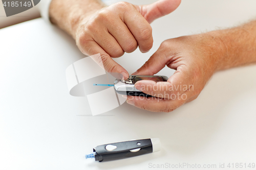 Image of senior man with glucometer checking blood sugar