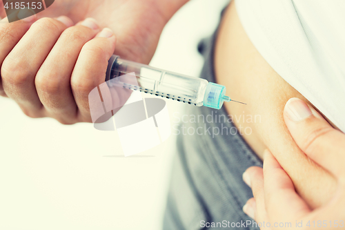 Image of close up of hands making injection by insulin pen