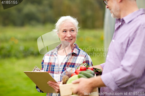 Image of senior couple with box of vegetables on farm