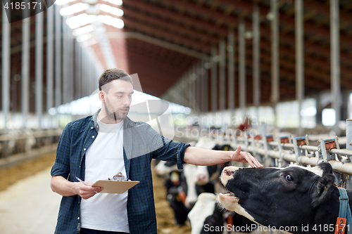 Image of farmer with clipboard and cows in cowshed on farm