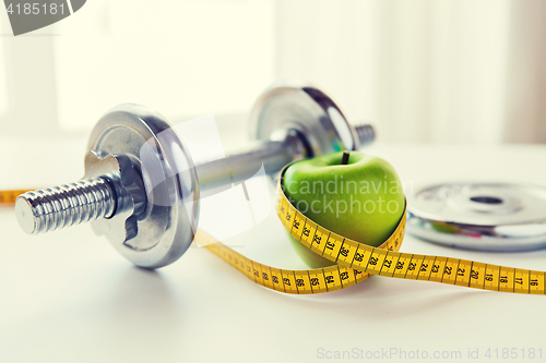 Image of close up of dumbbell and apple with measuring tape